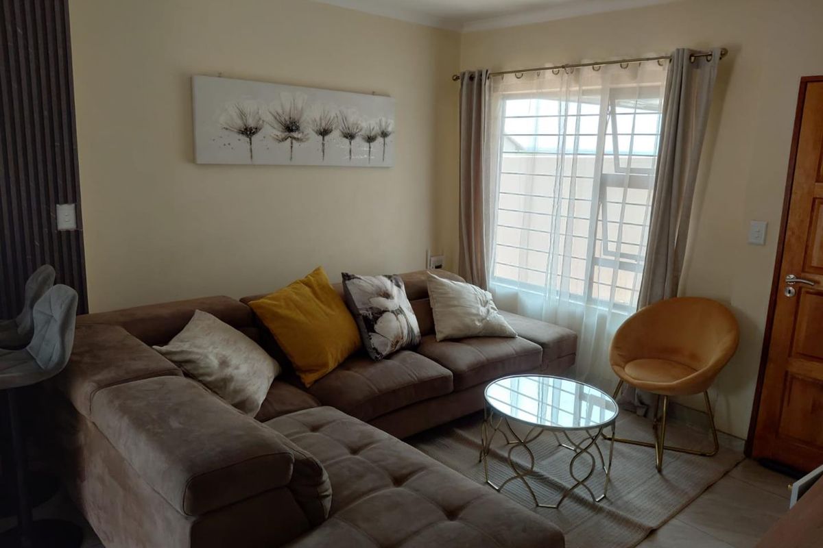 A cozy living room featuring tiled flooring, a window with security bars, and neutral wall finishes.
