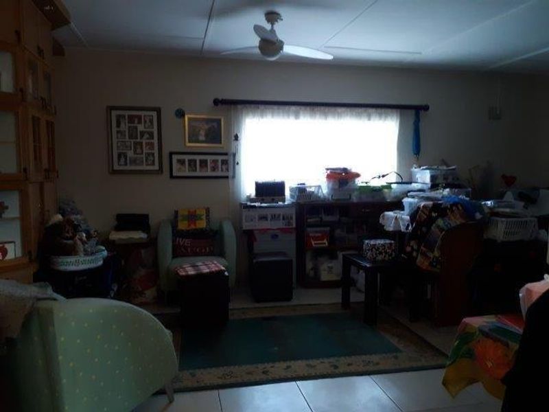 A living room area featuring tiled flooring and a ceiling fan, currently used as a multi-purpose space.