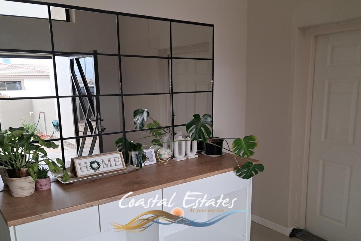 A bright living area featuring a modern grid-style wall mirror and built-in cabinetry, providing a clean and contemporary aesthetic.