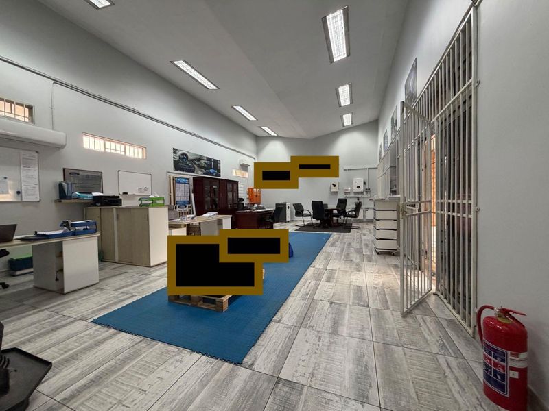 Spacious commercial office area featuring tiled flooring, fluorescent lighting, and secure access gate, suitable for a professional business environment.