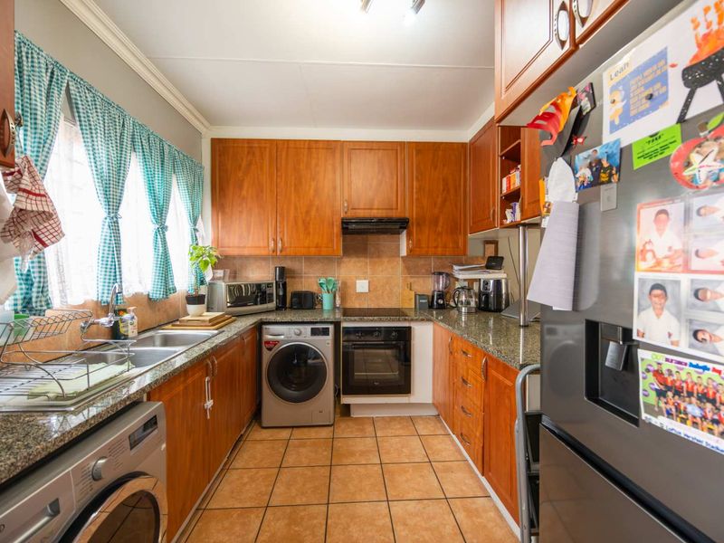 Functional kitchen featuring warm-toned wooden cabinetry, granite countertops, tiled backsplash, and integrated appliances including an oven and hob.
