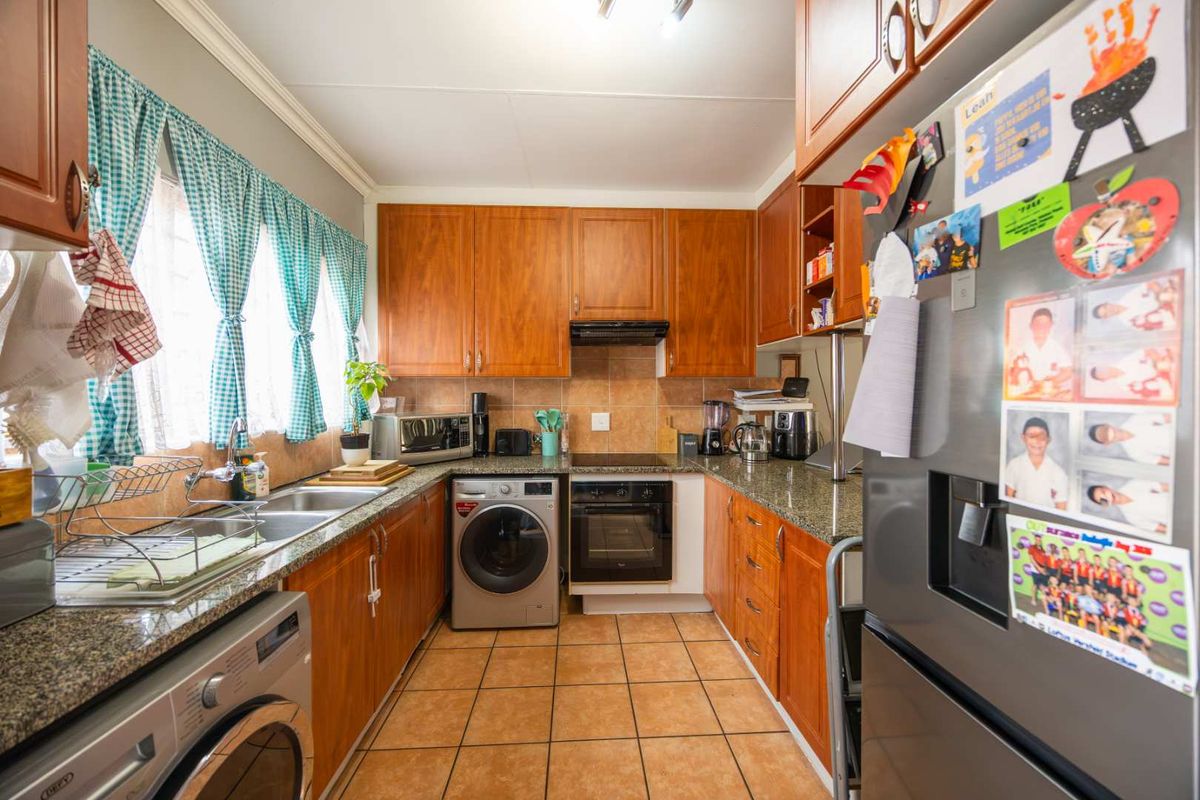 Functional kitchen featuring warm-toned wooden cabinetry, granite countertops, tiled backsplash, and integrated appliances including an oven and hob.