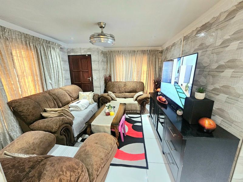 A living room featuring tiled flooring, decorative wall tiles, and a ceiling fan, providing a functional space for relaxation.