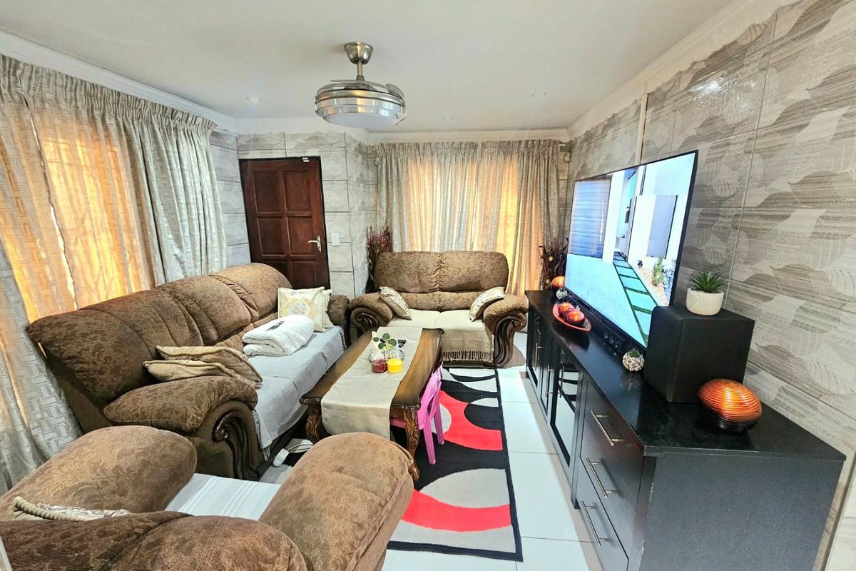 A living room featuring tiled flooring, decorative wall tiles, and a ceiling fan, providing a functional space for relaxation.