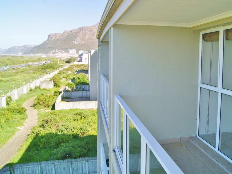 A private balcony featuring a glass balustrade and tiled flooring, offering scenic views of the surrounding landscape and mountain range.