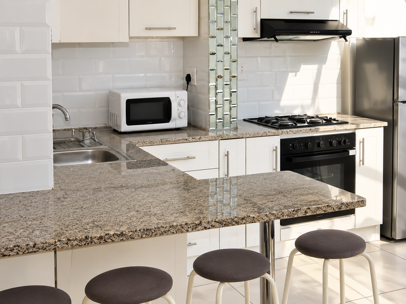 A well-maintained kitchen featuring granite countertops, subway tile backsplash, built-in oven with gas hob, and integrated cabinetry.