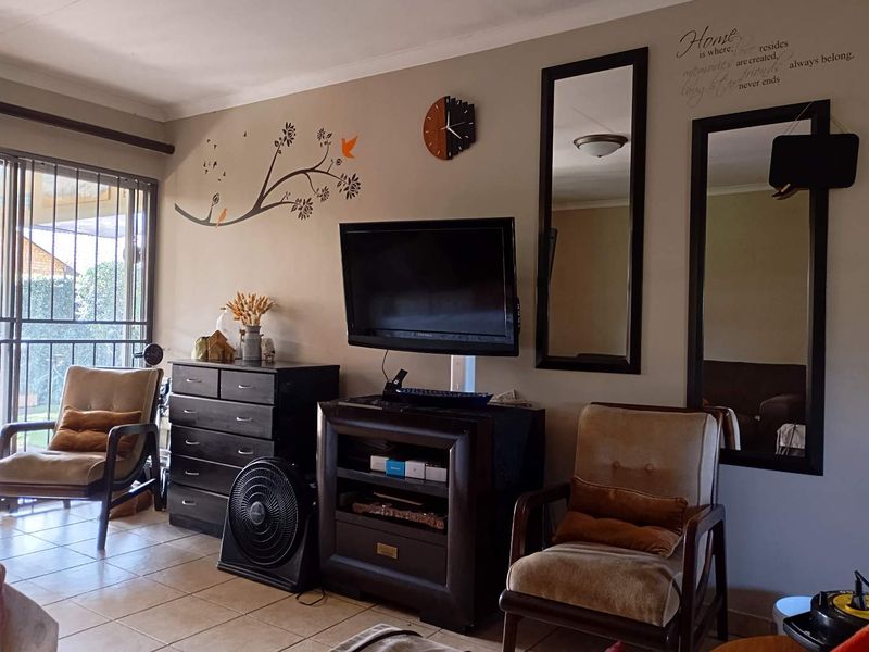 A living room featuring tiled flooring and a sliding glass door with a security gate, providing access to the exterior.