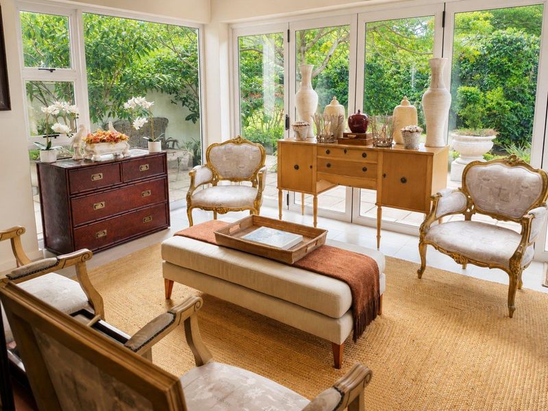 Bright and airy living room featuring expansive floor-to-ceiling glass doors that provide seamless access and views to the lush garden.
