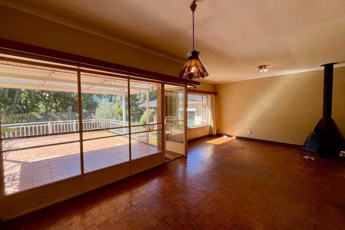Spacious living area featuring original parquet flooring, a built-in fireplace, and large sliding glass doors opening onto a covered patio.