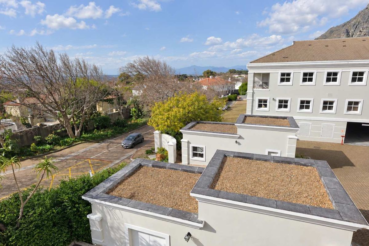 An elevated aerial view of the office property complex, showcasing the paved driveway, parking garage access, and surrounding landscaped grounds.