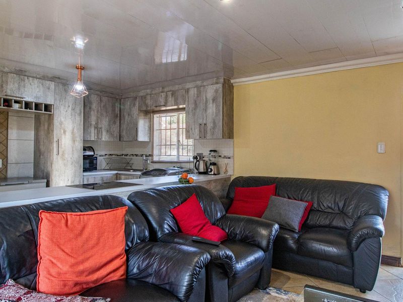 Open plan living area featuring a kitchen with wood-look cabinetry and a breakfast bar, seamlessly flowing into the lounge space with direct outdoor access.