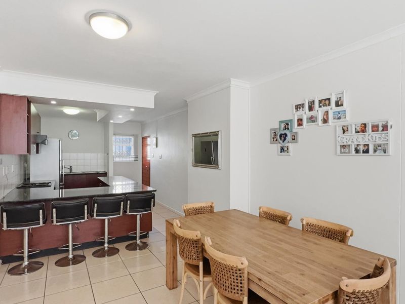 Open-plan living and dining area featuring a functional kitchen with dark wood cabinetry, granite countertops, and tiled flooring throughout.