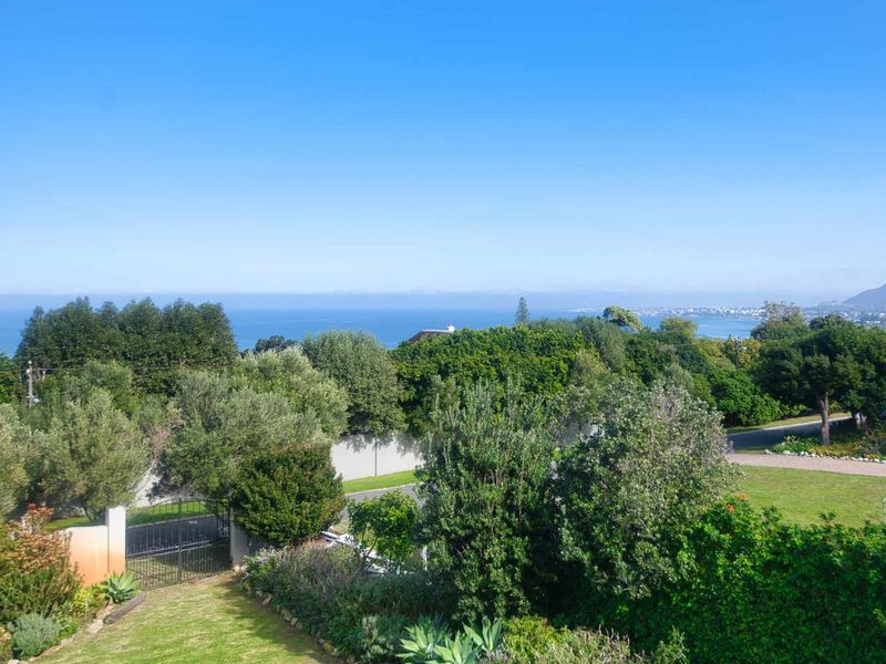 A scenic elevated view overlooking the lush garden, boundary wall, and distant coastal landscape.