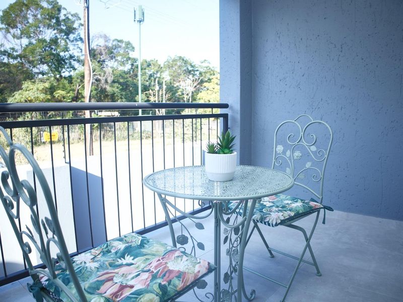 A private balcony featuring a metal balustrade, tiled flooring, and a textured wall finish, offering an outdoor space for relaxation.