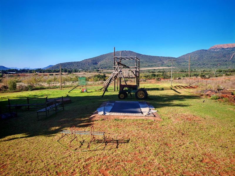 Expansive outdoor garden area featuring open lawn space, mountain views, and perimeter fencing in a rural setting.