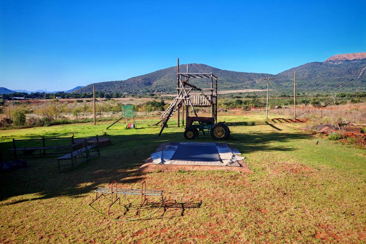 Expansive outdoor garden area featuring open lawn space, mountain views, and perimeter fencing in a rural setting.