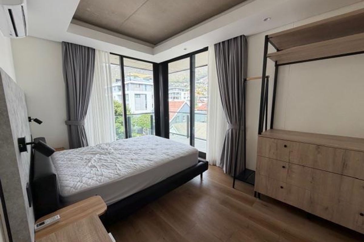 Modern bedroom featuring floor-to-ceiling windows, access to a private balcony, recessed ceiling detail, and integrated air conditioning unit.