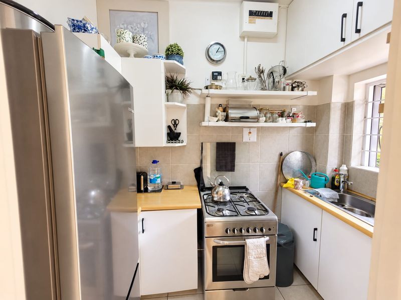 Compact kitchen featuring white cabinetry, wooden countertops, a gas stove with oven, and a stainless steel sink with tiled backsplash.