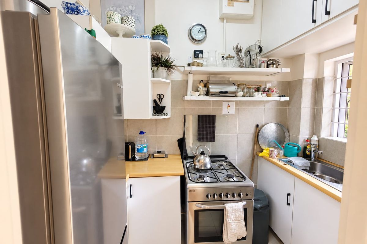 Compact kitchen featuring white cabinetry, wooden countertops, a gas stove with oven, and a stainless steel sink with tiled backsplash.