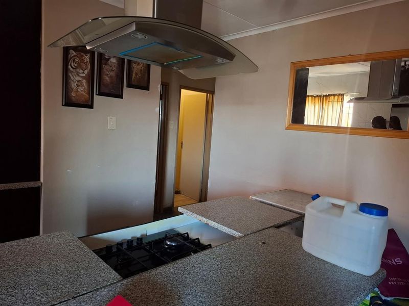 Kitchen area featuring a gas hob, stainless steel extractor fan, and granite countertops with built-in cabinetry.