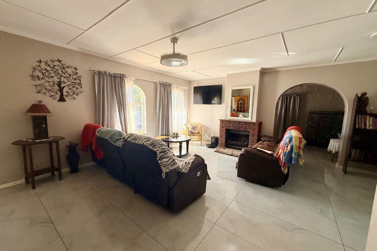 Spacious living room featuring large format floor tiles, a brick fireplace, and an arched entryway leading to an adjacent space.