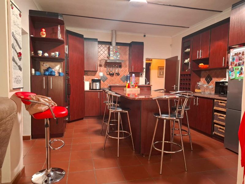 A spacious kitchen featuring dark wood cabinetry, a central island with granite countertops, and tiled flooring, offering a functional layout for cooking and dining.
