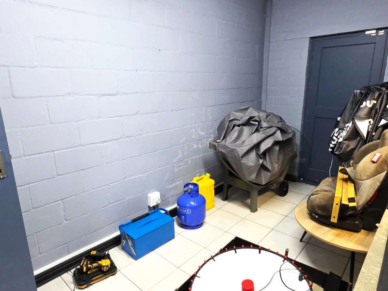 A functional utility space featuring durable tiled flooring and painted concrete block walls, suitable for storage or workshop use.
