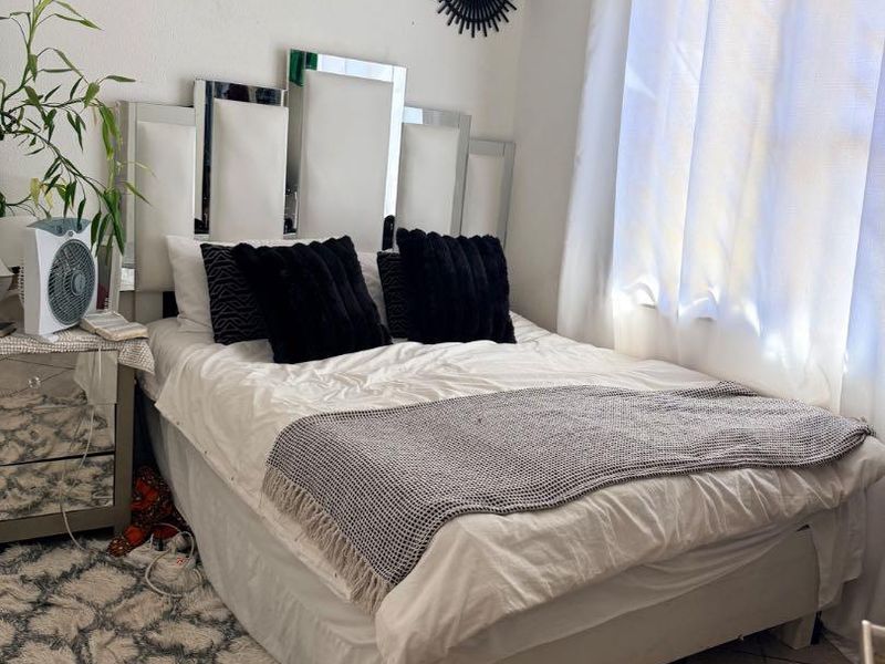 A bedroom featuring tiled flooring and a window with a curtain rod, providing a functional space for rest.