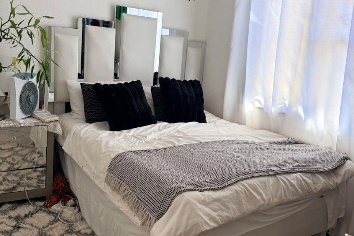A bedroom featuring tiled flooring and a window with a curtain rod, providing a functional space for rest.