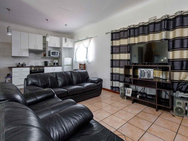 Open-plan living area featuring tiled flooring and a compact kitchen with built-in cabinetry, oven, and extractor fan.