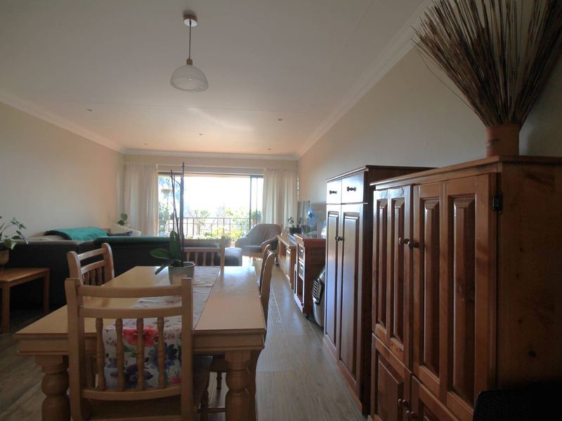 Open-plan living and dining area featuring laminate flooring, recessed lighting, and a sliding glass door leading to an outdoor balcony.