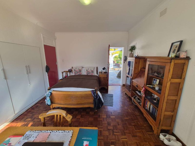 A bedroom featuring classic parquet flooring, built-in cupboards, and direct access to an outdoor patio area.