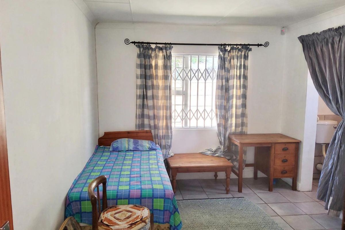 A functional bedroom featuring tiled flooring, a window with a security gate, and coving detail.