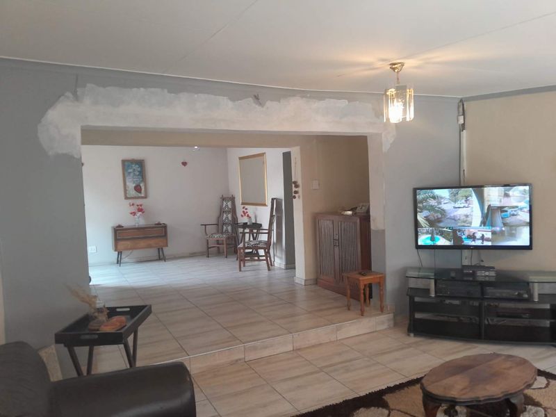 Living area featuring tiled flooring and a raised floor section, currently showing unfinished plasterwork around the central archway.