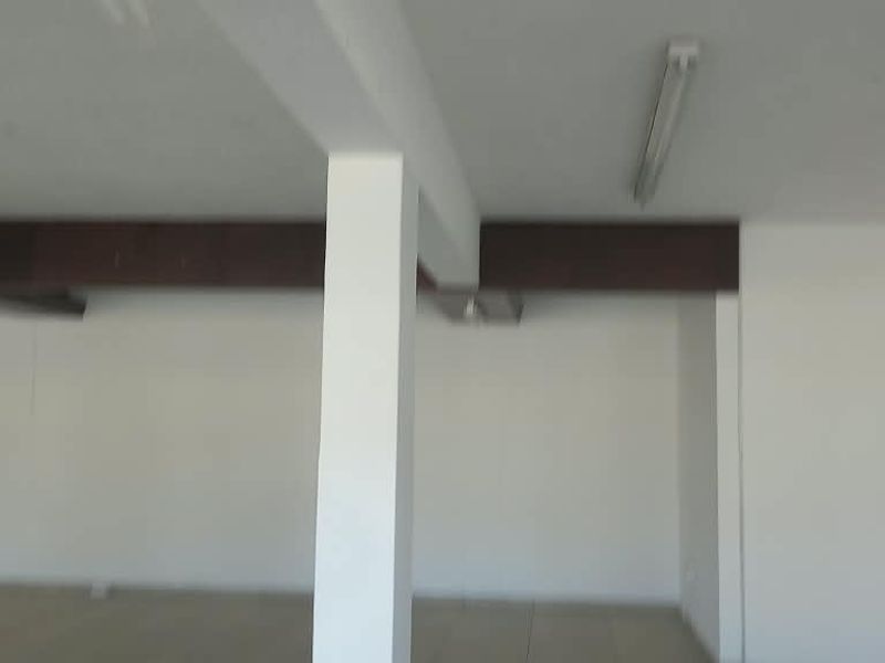 A spacious, open-plan retail area featuring tiled flooring, support columns, and functional overhead lighting, offering a versatile layout for various business needs.