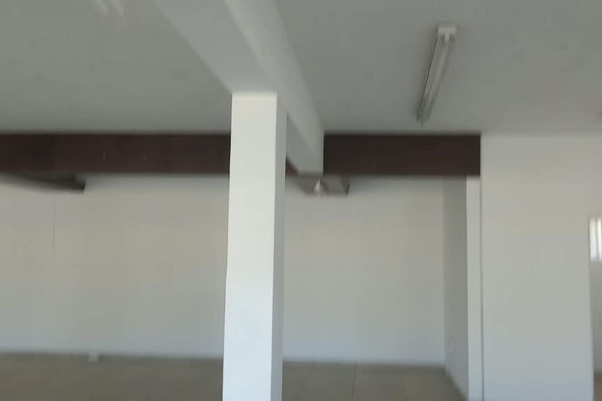 A spacious, open-plan retail area featuring tiled flooring, support columns, and functional overhead lighting, offering a versatile layout for various business needs.