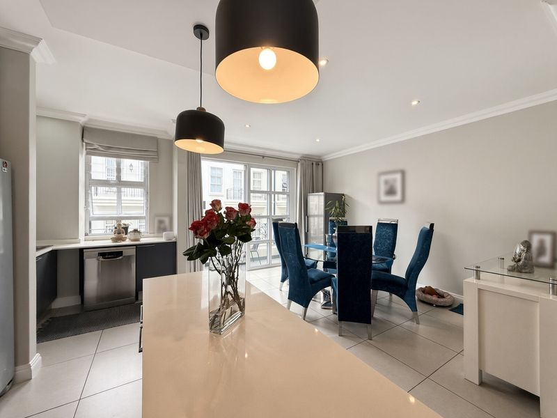 Modern open-plan kitchen and dining area featuring a central island, stone countertops, integrated appliances, and sliding glass doors leading to an outdoor space.