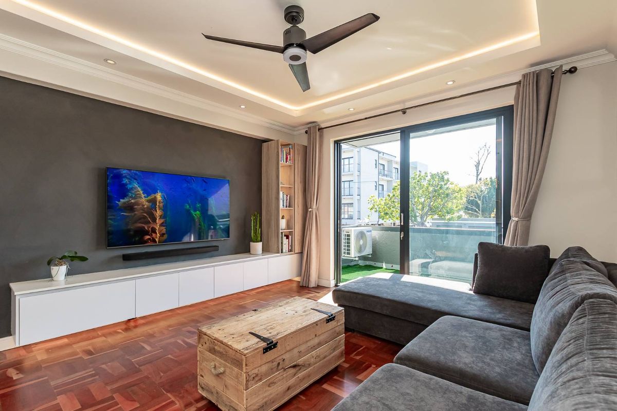 Modern living room featuring parquet flooring, recessed cove lighting, a ceiling fan, and built-in cabinetry, with direct access to a private balcony.