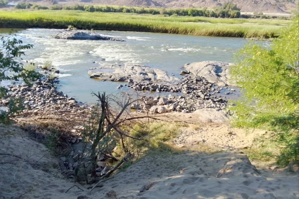 A scenic view of the river flowing through the property, featuring natural rock formations and sandy banks.