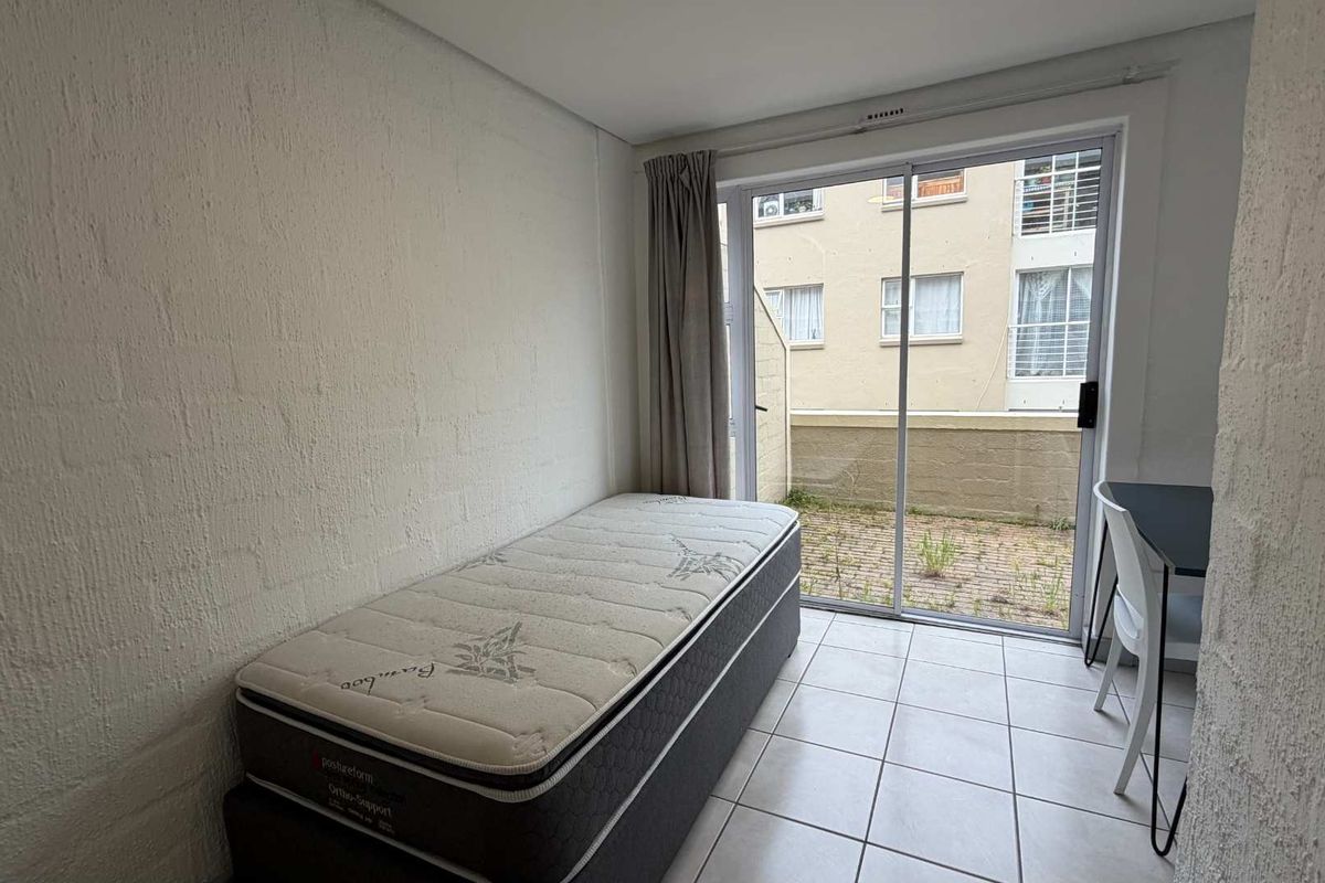 A bedroom featuring tiled flooring and a sliding glass door providing direct access to a small exterior patio area.