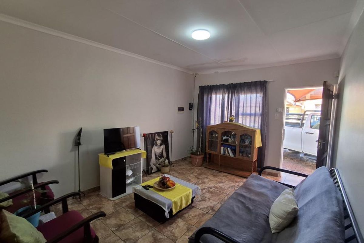 A living room featuring tiled flooring and direct access to the exterior, with visible ceiling water staining requiring attention.
