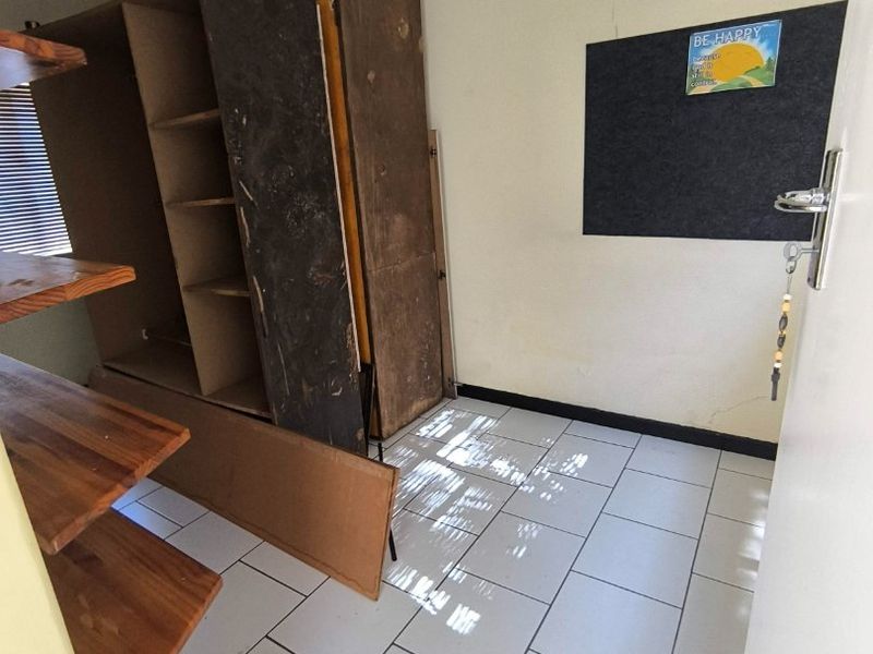 A bedroom featuring tiled flooring and built-in shelving, currently requiring cosmetic updates and wall repairs to improve its overall condition.