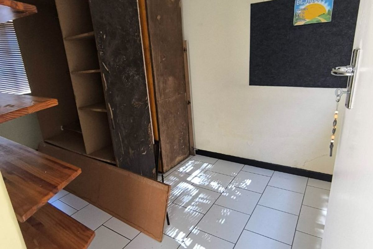A bedroom featuring tiled flooring and built-in shelving, currently requiring cosmetic updates and wall repairs to improve its overall condition.