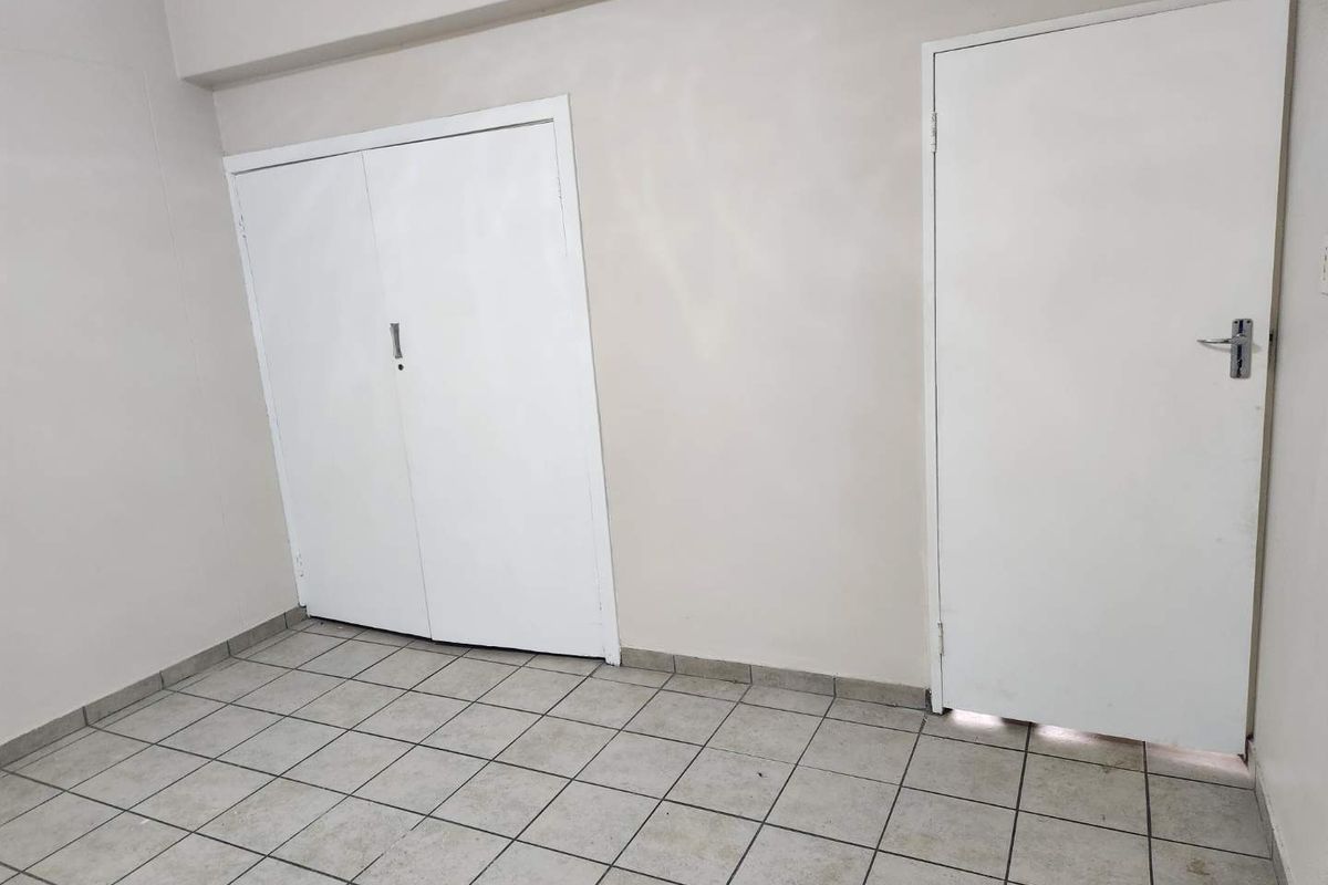 An empty bedroom featuring tiled flooring and built-in cupboards, providing a blank canvas for potential interior design updates.