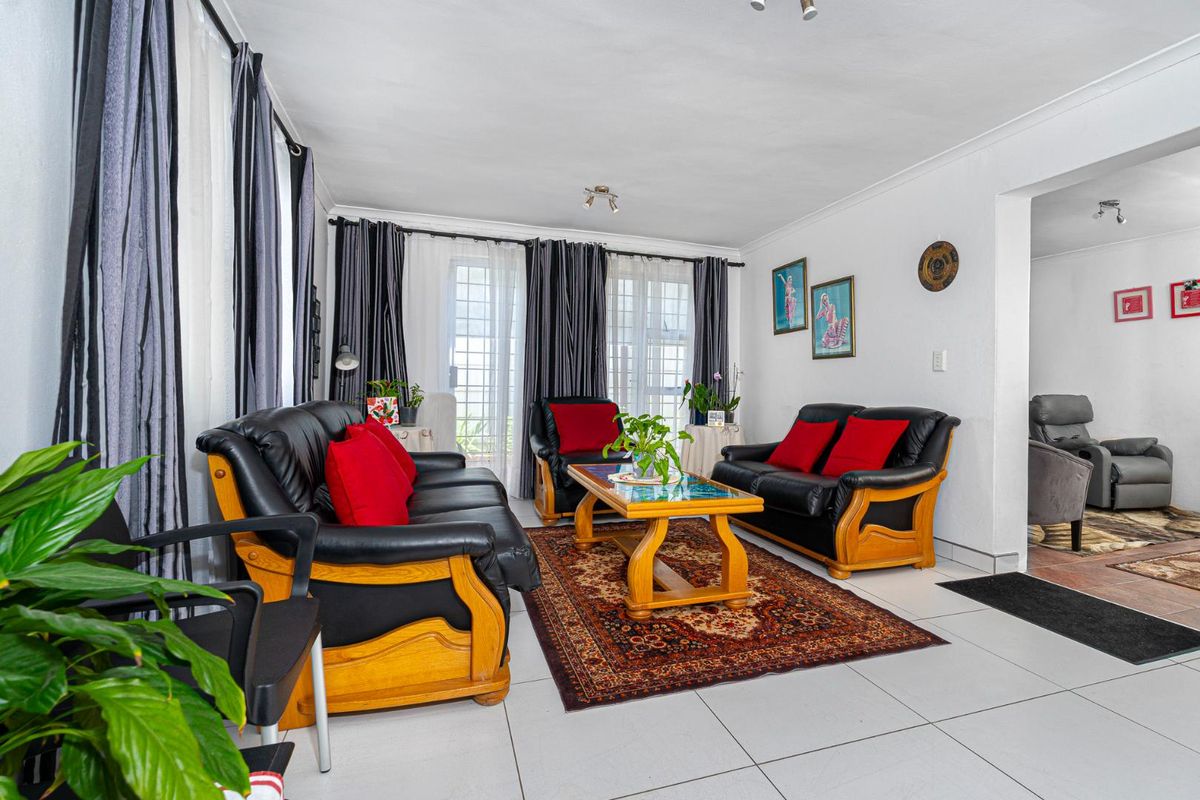 A bright living room featuring large glass sliding doors, tiled flooring, and neutral walls, providing a comfortable and functional space for relaxation.