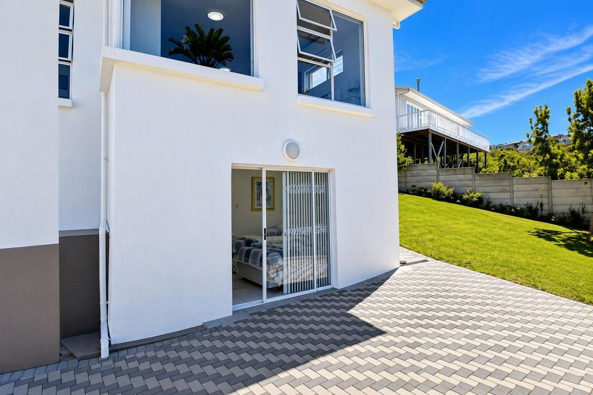 Rear view of the property featuring a paved patio area, sliding door access, and well-maintained exterior walls with modern aluminium window frames.