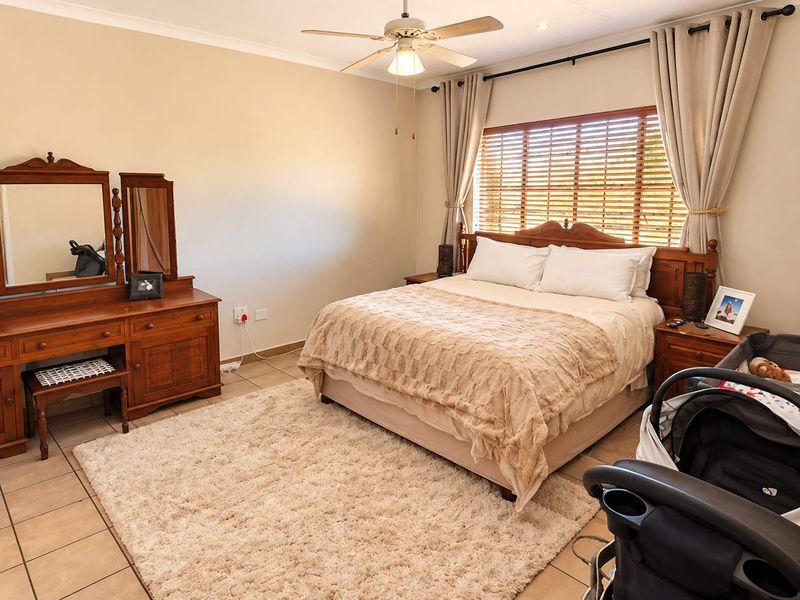 A well-maintained bedroom featuring tiled flooring, a ceiling fan, and window blinds, providing a comfortable and functional living space.