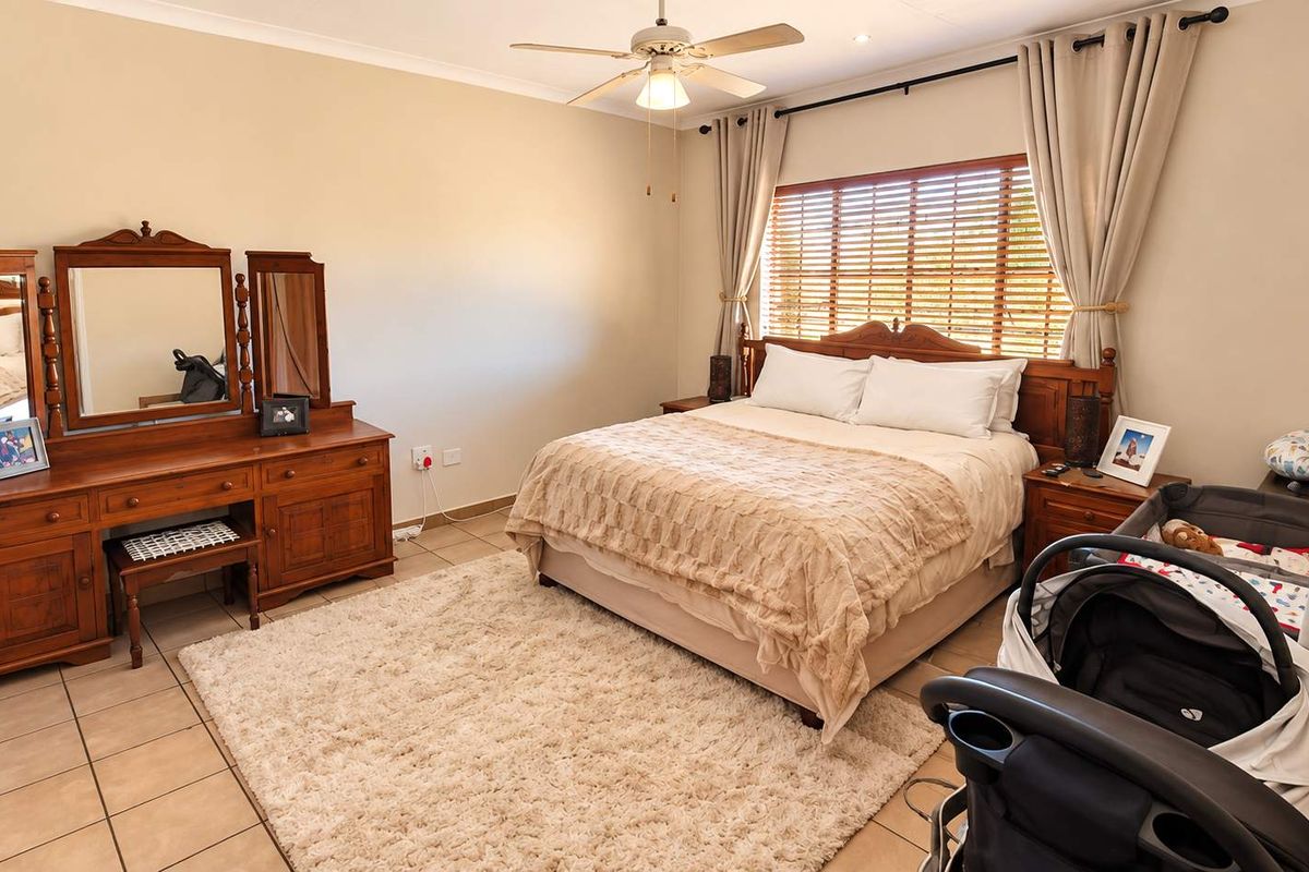 A well-maintained bedroom featuring tiled flooring, a ceiling fan, and window blinds, providing a comfortable and functional living space.