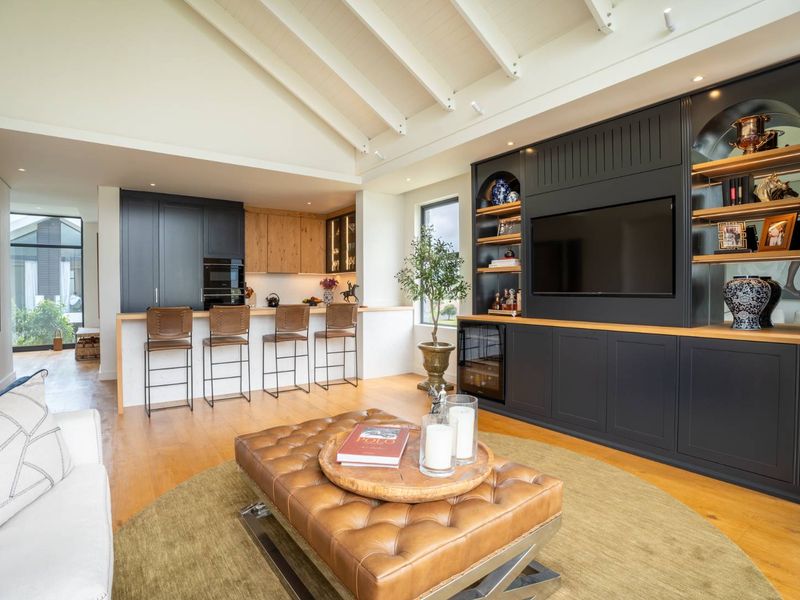 Spacious open-plan living area featuring a vaulted ceiling with exposed rafters, custom built-in cabinetry, and a modern kitchen with a breakfast bar.