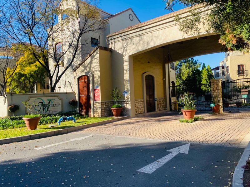The main entrance to Morningside Village Estate, featuring a secure gated access point with stone-clad pillars and a paved driveway.